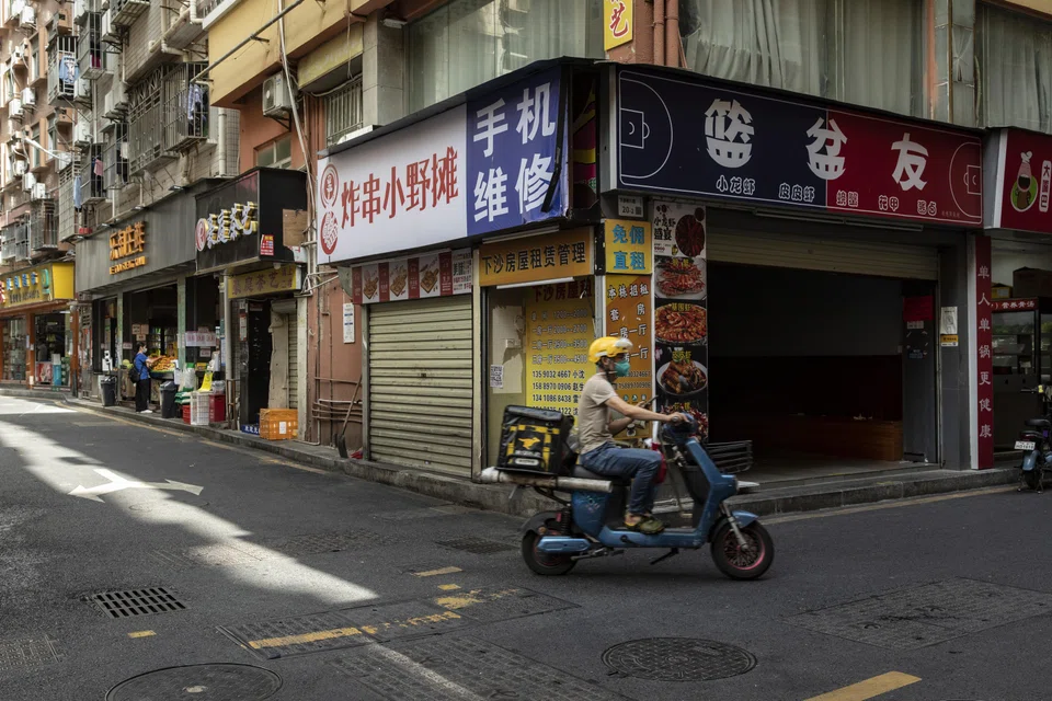 A food deliverer rides past shuttered stores at Xiasha Village in Shenzhen, China on Nov 16, 2022. In October, the IMF cut its projection for the world’s number two economy to 3.2 per cent this year as it is weighed down by Covid-zero policies.
