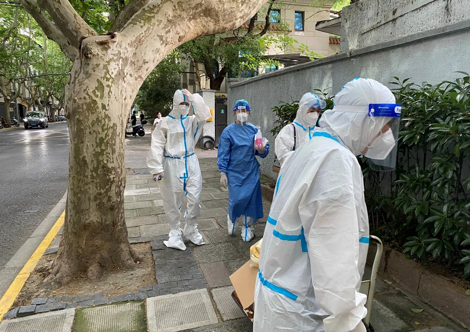 FILE PHOTO: Workers in protective suits walk on a street, following the coronavirus disease (COVID-19) outbreak, in Shanghai, China June 9, 2022. REUTERS/Andrew Galbraith/File Photo