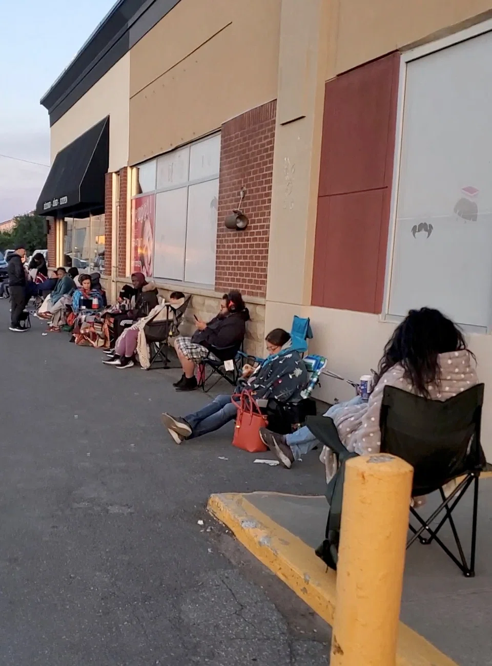 People wait outside the passport office to submit their application, in Montreal, Canada on June 20, 2022.