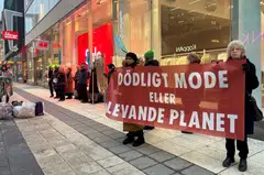 Climate activists hold up a sign in Swedish  "Deadly fashion or living planet?" outside a H&M store in Stockholm, Sweden, Jan 31, 2024. 
