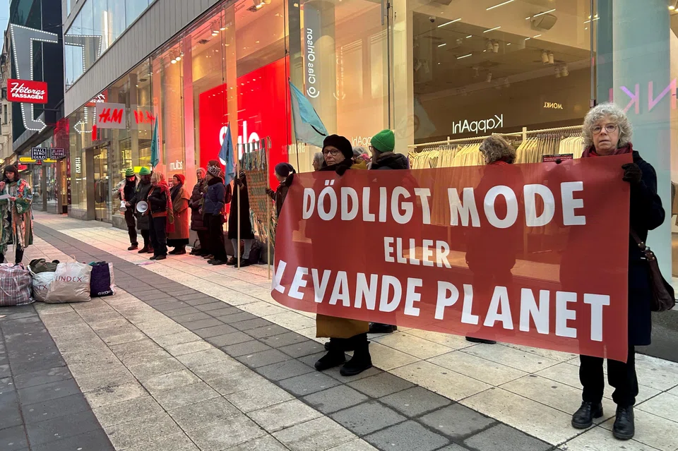 Climate activists hold up a sign in Swedish  "Deadly fashion or living planet?" outside a H&M store in Stockholm, Sweden, Jan 31, 2024. 