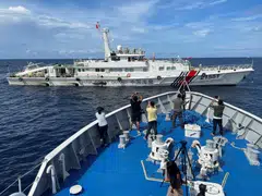 Journalists onboard a Philippines Coast Guard ship take photos of a China Coast Guard vessel, during a resupply mission for troops stationed at a grounded Philippines ship, in the South China Sea, Sept 8, 2023. 