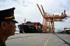 A border guard stands near a cargo ship at Tan Vu port in Hai Phong near Hanoi. Vietnam seeks to be a transshipment hub and a critical node of the supply chain between Asean and China.