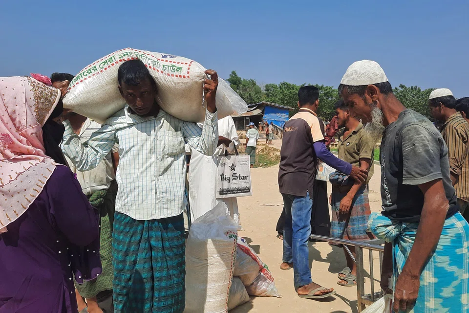 Rohingya refugees carrying relief supplies after collecting them in a refugee camp in Ukhia in Bangladesh on Mar 2.  A drastic fall in aid pledges last year left only US$553 million to meet their needs, well below the funds sought by aid agencies. 