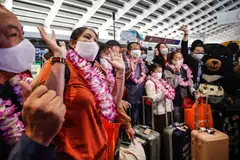 Passengers, part of the first tourist group arriving from Thailand, pose for the media at Taoyuan International Airport in Taoyuan on Oct 13, 2022, after Taiwan reopened its borders by ending mandatory Covid quarantine for arrivals.