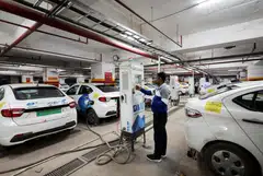 A man charges an electric vehicle at  a BluSmart Electric Mobility charging hub in Gurugram, India, Dec 9, 2022. 