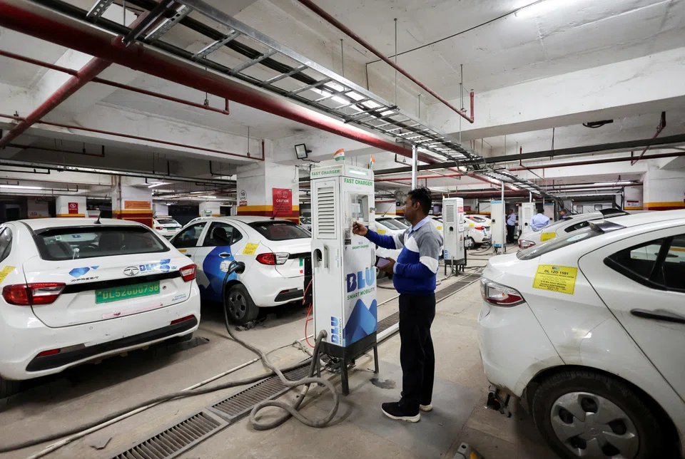 A man charges an electric vehicle at  a BluSmart Electric Mobility charging hub in Gurugram, India, Dec 9, 2022. 