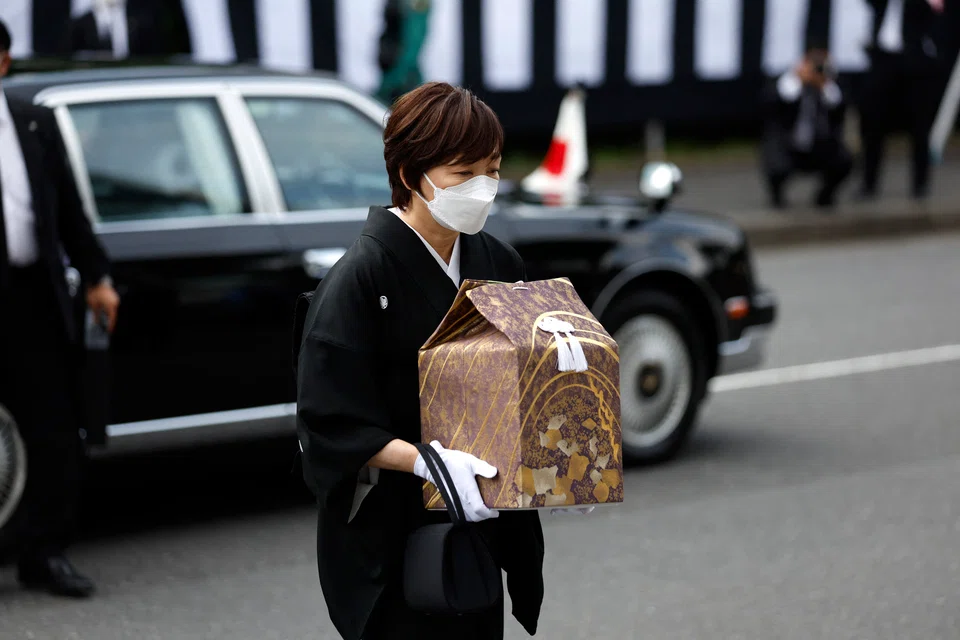 Akie Abe, wife of Japan's former prime minister Shinzo Abe, carries a cinerary urn containing his ashes as she arrives to attend her husband's state funeral at the Nippon Budokan in Tokyo.