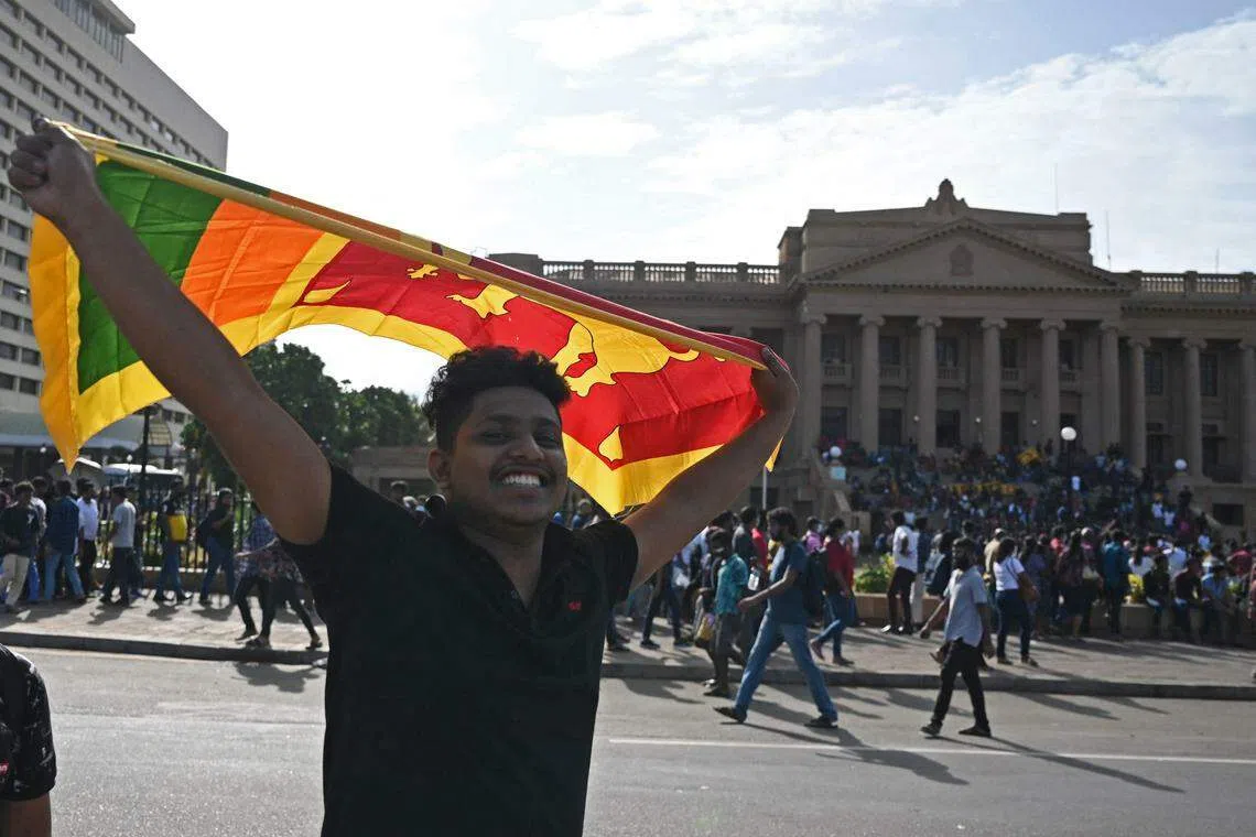 A man waves Sri Lanka's national flag outside presidential secretariat in Colombo on July 13, 2022. The country is mired in a deep political and economic crisis, and on July 13, the country's president flew out of the country days after a huge crowd of protesters stormed his residence.
