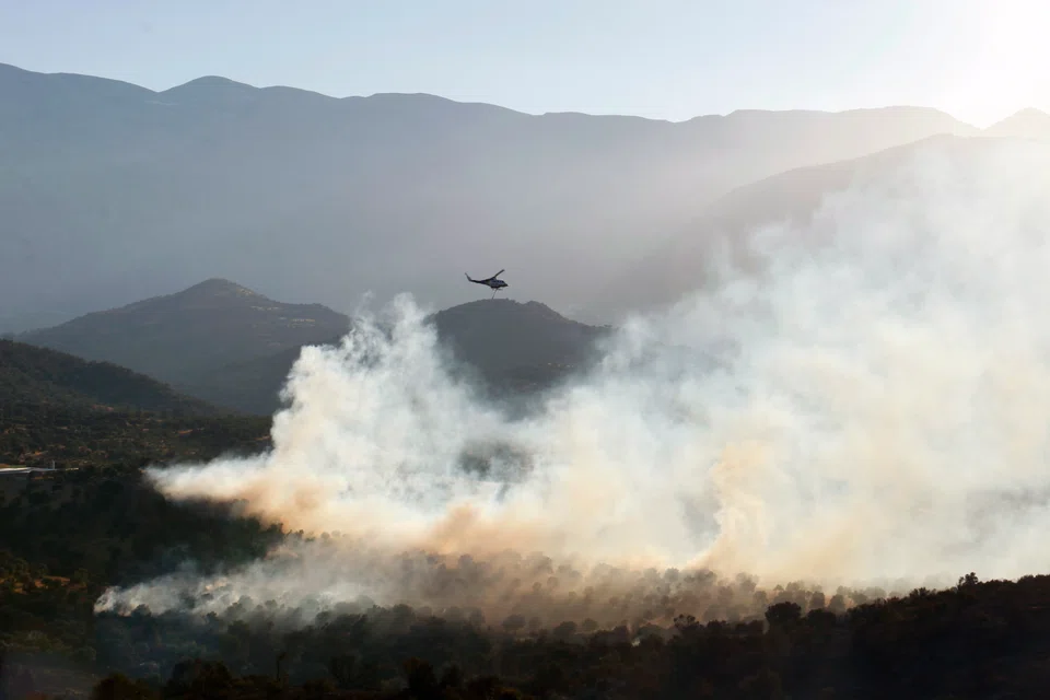 A firefighting helicopter drops water  to extinguish a fire in Agia Galini village in municipality of Agios Vassilios, Rethimno, Greece, 16 July 2022. 