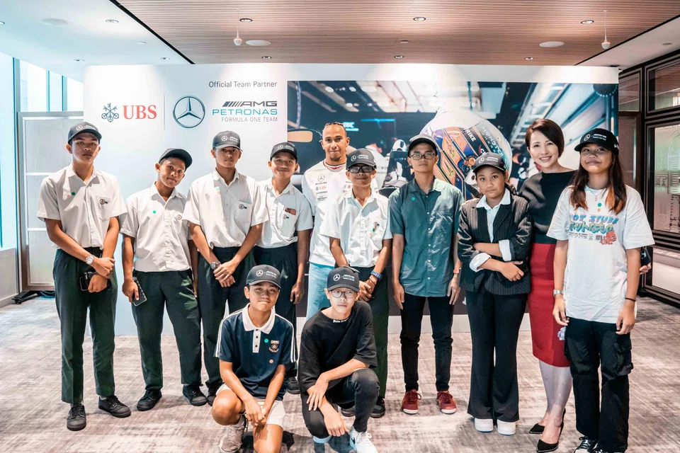 F1 driver Lewis Hamilton (fifth from left) met with children from UBS Singapore’s community partners through various social service agencies on Sep 14, 2023. With them is UBS Singapore country head Jin Yee Young (second from right).