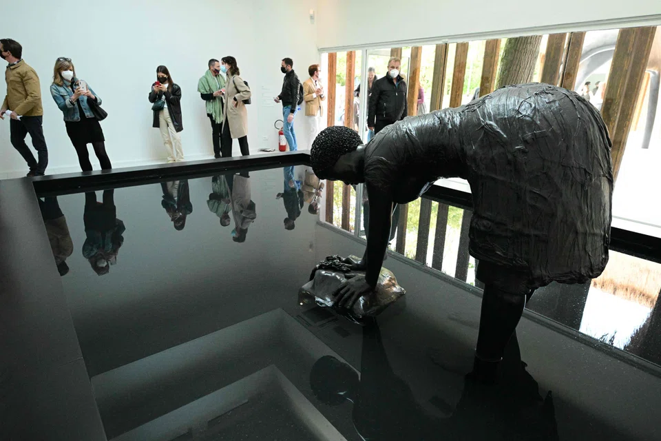 Visitors view "Last Garment", a sculpture based on a vintage postcard of a washerwoman in Jamaica, part of US artist Simone Leigh's Venice exhibition entitled "Sovereignty", during a press day at the 59th Venice Art Biennale in Venice on April 20, 2022. - Eighty countries, including Ukraine, will have a pavilion at the 59th Biennale, which is set to begin on April 23 and runs through November. (Photo by Vincenzo PINTO / AFP) / RESTRICTED TO EDITORIAL USE - MANDATORY MENTION OF THE ARTIST UPON PUBLICATION - TO ILLUSTRATE THE EVENT AS SPECIFIED IN THE CAPTION