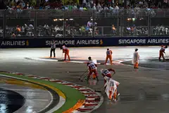 The Singapore Formula One Grand Prix has been delayed by an hour; stewards sweeping water from the track after heavy rain.