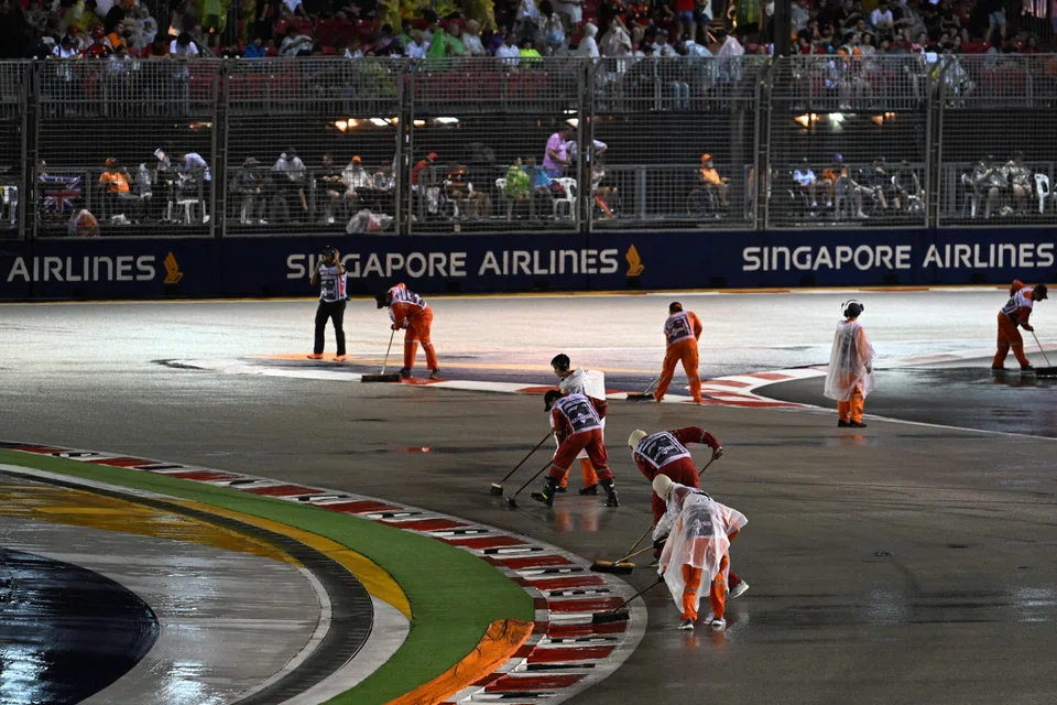 The Singapore Formula One Grand Prix has been delayed by an hour; stewards sweeping water from the track after heavy rain.