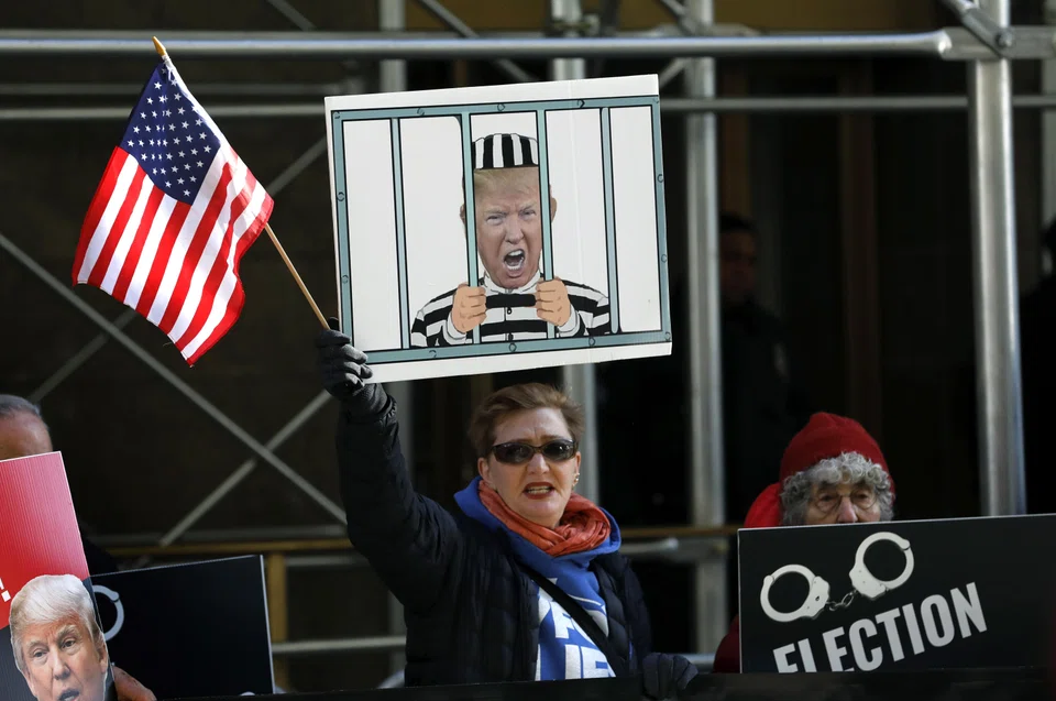 A demonstrator shouts and holds up a sign outside New York Criminal Court in advance of a potential Indictment of former President Donald Trump in New York, March 21, 2023. 