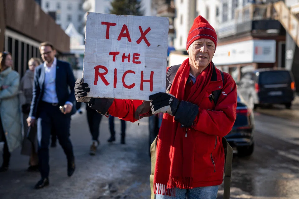 Phil White, a British millionaire poses with a placard reading "Tax the rich" next to the Congress centre during the World Economic Forum annual meeting in Davos on Jan 18, 2023. 