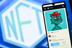 This file photo taken in London on December 30, 2021 shows a PsychoKitty NFT (Non-Fungible Token) created by psychedelic artist Ugonzo displayed on a phone and a NFT logo displayed on a computer screen from a Crypto.com NFT marketplace.  The market for certified digital objects, also known as NFTs, is suffering a rout at the moment with all the major cryptocurrencies slumping in value.