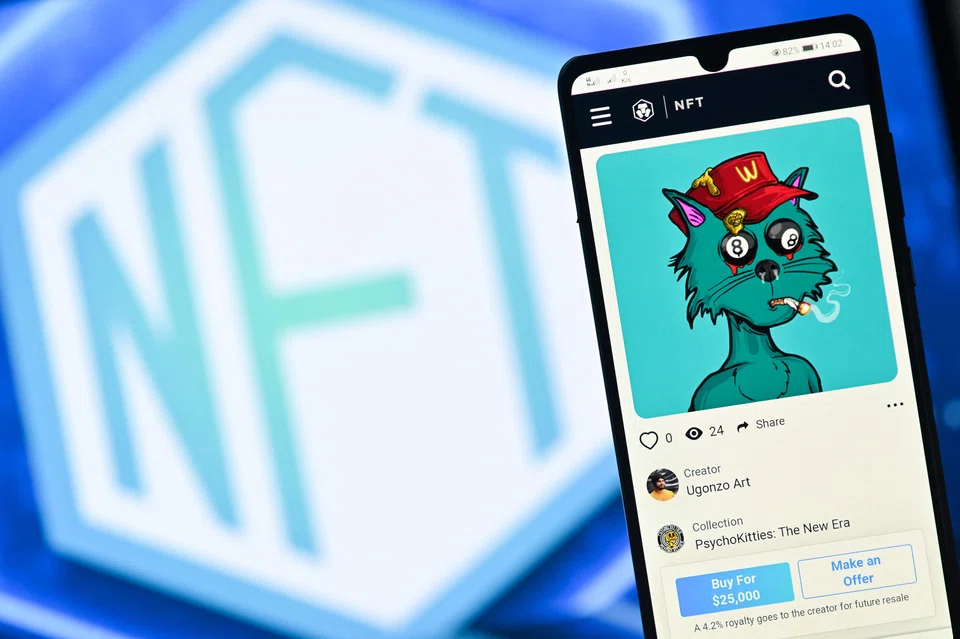 This file photo taken in London on December 30, 2021 shows a PsychoKitty NFT (Non-Fungible Token) created by psychedelic artist Ugonzo displayed on a phone and a NFT logo displayed on a computer screen from a Crypto.com NFT marketplace.  The market for certified digital objects, also known as NFTs, is suffering a rout at the moment with all the major cryptocurrencies slumping in value.