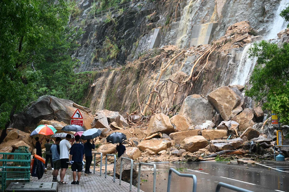 Plainclothes officials and police look at a landslide covering a road at Yiu Tung Estate in Shau Kei Wan in Hong Kong on Sept 8, 2023, following heavy rains. 