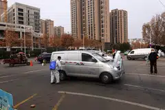 A staff member (L) sprays disinfectant on a van outside a market in Xi'an in China's northern Shaanxi province on January 10, 2022. Businesses, schools and restaurants in Xi’an will close for one week, officials said Tuesday (July 5), after the Chinese city logged a handful of Covid-19 cases as outbreaks nationwide strain Beijing’s zero-tolerance virus approach.