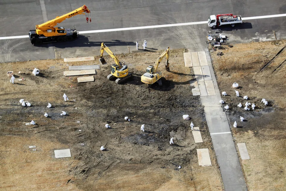 Officials remove the wreckage of burnt Japan Airlines' (JAL) Airbus A350 after a collision with a Japan Coast Guard aircraft at Haneda international airport in Tokyo, Japan, Jan 7, 2024.