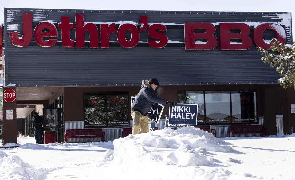 A campaign volunteer places signs in a snow bank for Former South Carolina Governor and Republican presidential candidate Nikki Haley before the start of a campaign event at Jethro’s BBQ in Ames, Iowa, Jan 14, 2024. 