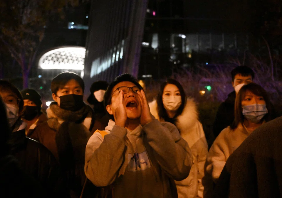 TOPSHOT - A protester shouts during a protest for the victims of a deadly fire as well as a protest against China's harsh Covid-19 restrictions in Beijing on Nov 28, 2022