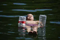 A man uses water bottles for flotation as he cools off in a canal in Beijing. Swathes of northern China sweltered in 40 deg C on June 22.