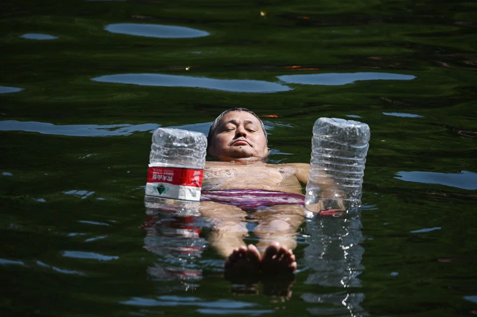 A man uses water bottles for flotation as he cools off in a canal in Beijing. Swathes of northern China sweltered in 40 deg C on June 22.