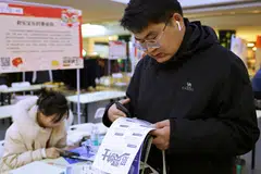 Zhang Baichuan, 23, checks a job advertisement at a job fair in Shijiazhuang, Hebei province.