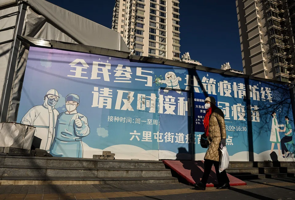 A woman wearing a face mask amid the Covid-19 pandemic walks along a street in Beijing on December 11, 2022. (Photo by Noel CELIS / AFP)