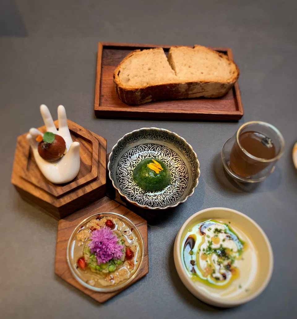 Snacks include silken cheese, sourdough bread, cherry tomato bon bon, artichoke salad and Shanklish cheese.