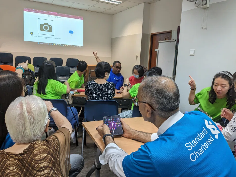 StanChart volunteers helping seniors with their smartphone queries at a digital clinic. The bank hopes to encourage more seniors to embrace technology.