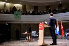 Students deploy a protest banner which reads "President of violence and hypocrisy" during French President Emmanuel Macron's speech to the Nexus Institute in The Hague on April 11, 2023 as part of a state visit to the Netherlands. 