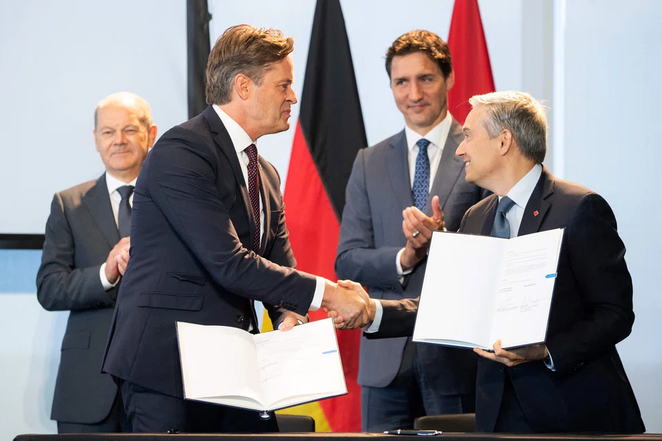 German Chancellor Olaf Scholz (left) and Canadian Prime Minister Justin Trudeau (right) watch as Volkswagen AG's CEO Herbert Diess (second left) shakes hands with Canadian Minister of Innovation, Science and Industry, Francois-Philippe Champagne at the Canadian-German Chamber of Industry and Commerce in Toronto, Canada, on Aug 23, 2022. 
