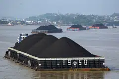 Barges transporting coal on the Mahakam River in  Indonesia. The world urgently needs to wean off fossil fuels, but this has been difficult with soaring inflation.
