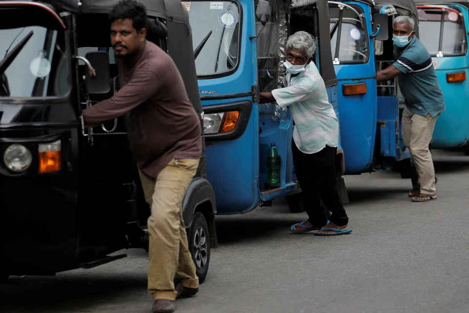 Drivers push their three-wheelers while waiting in a line to buy petrol at a Ceylon Ceypetco fuel station on a main road, amid the country's economic crisis in Colombo, Sri Lanka.