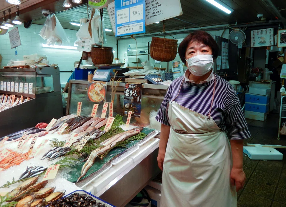 Kaoru Kimura, an employee of the fish store Kimura, poses for a photograph in front of her store at Nishiki Market in Kyoto, western Japan June 18, 2022. 