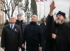 Russian President Vladimir Putin, flanked by Sevastopol Governor Mikhail Razvozhayev (left), and Metropolitan Tikhon Shevkunov (right), chairman of the Patriarchal Council for Culture, as he visits the Chersonesos Taurica historical and archeological park during a visit to Crimea on the ninth anniversary of its annexation by Russia from Ukraine.