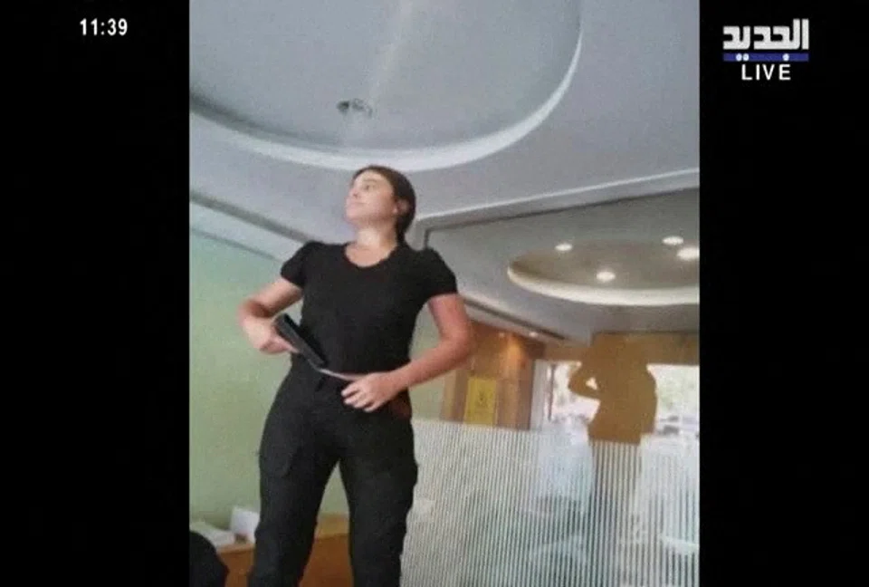 A woman, identified as Sally Hafez, is seen carrying what appears to be a gun at a Blom Bank branch in Beirut on Sep 14, 2022. 