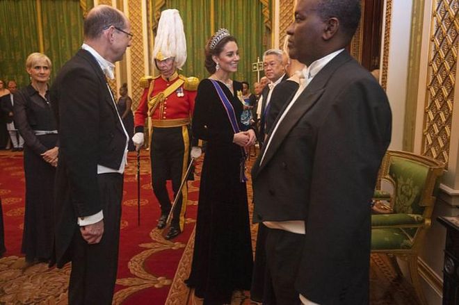 Kate speaks to guests with a smile. She wears a long, velvet gown by Alexander McQueen, paired with the Lover's Knot tiara from the House of Garrard. Her blue sash symbolizes her Dame Grand Cross of the Royal Victorian Order honor from the Queen, while her yellow brooch signifies the Royal Family Order.

Photo: Getty