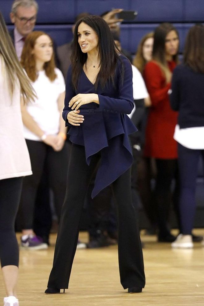 The Duchess of Sussex donned a navy blue Oscar de la Renta top and Altuzarra trousers with Aquazzura black suede heels for the Coach Core Awards at Loughborough University. She also decided to wear her hair straight for the first time and we're loving the sleek look. 