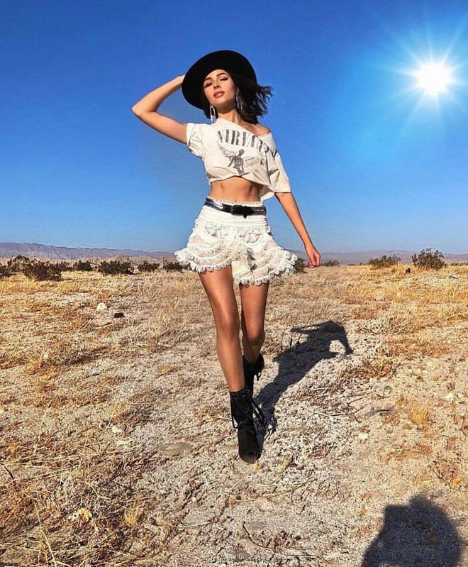 She channels her inner wild wild west vibe with a hat from Ruslan Baginskiy paired with a cropped Nirvana t-shirt and a white lace Zimmerman skirt.
  Photo: Instagram/@oliviaculpo