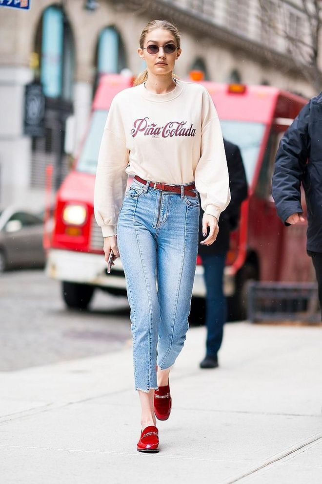 Gigi proves that dressing simply can still make a statement, just by adding the right punch of colour. That red belt and shoes are the perfect accessories to her Pina-Colada sweater. Photo: Getty 