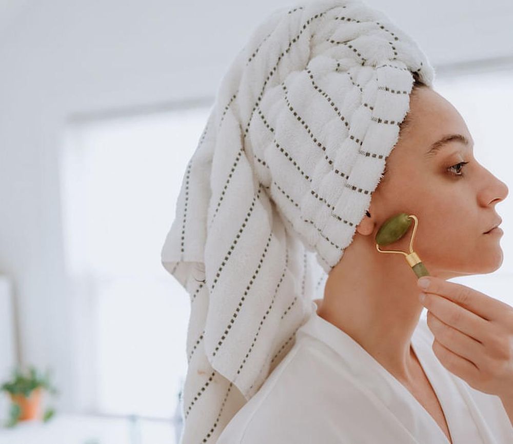 Woman using jade roller on her face at home