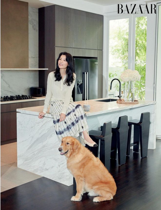 Relaxing with her dog Mao Mao on her kitchen counter in a top by Loro Piana, and her own skirt and Chanel pumps.