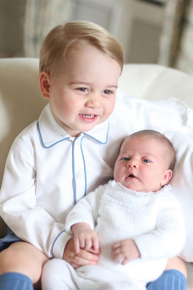 Prince George smiles while holding his newborn sister, Princess Charlotte, who was born on May 2, 2015. Kate Middleton captured the photo when her daughter was less than a month old, at the Duke and Duchess' country home, Anmer Hall, in Norfolk, England.