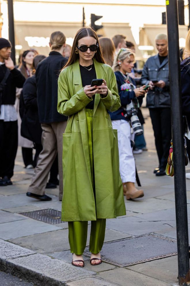 LONDON, ENGLAND - SEPTEMBER 18: A guest wears green leather coat, pants outside Simone Rocha during London Fashion Week September 2022 on September 18, 2022 in London, England. (Photo by Christian Vierig/Getty Images)