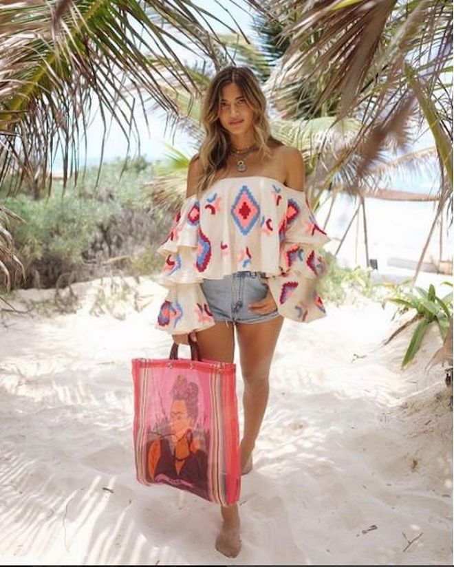 For the ultimate beachy vibe, pair an airy off-the-shoulder top with denim cutoffs. Add a colorful beach bag to top off the look. Photo: Instagram via @rocky_barnes
