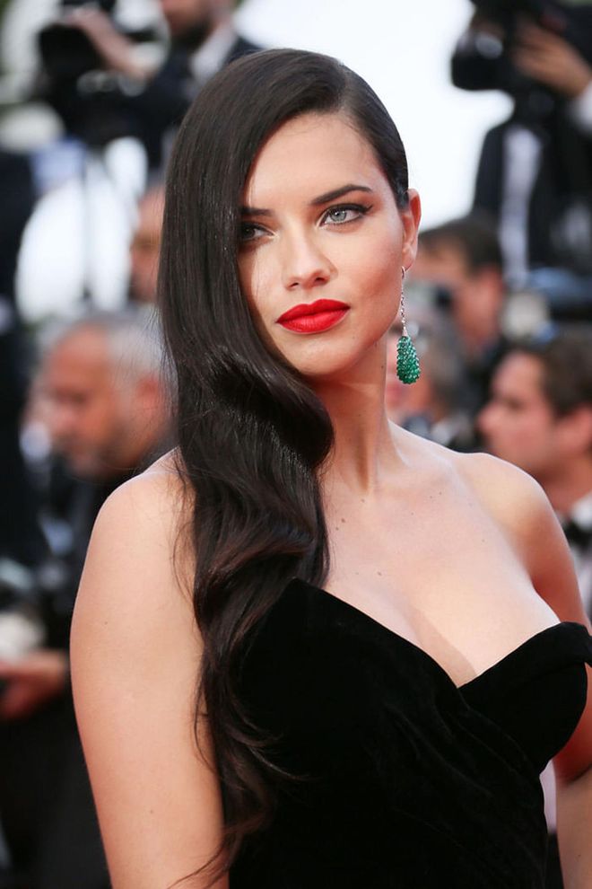 The model perfected the art of holiday dressing by adding a punchy red lip to complement her black dress and emerald earrings.
